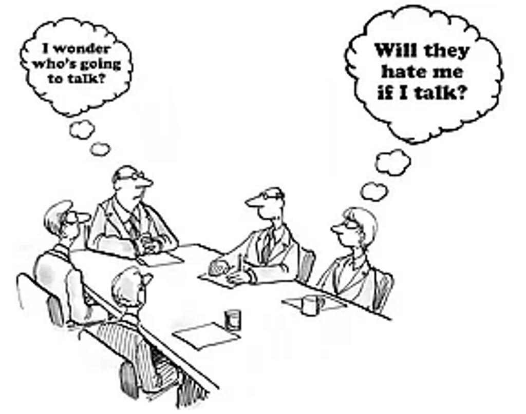 5 Menschen am Meetingtisch. Der Chef denkt "Wer wird wohl als erstes etwas sagen?" Die Frau denkt "Werden sie mich hassen, wenn ich etwas sage?"