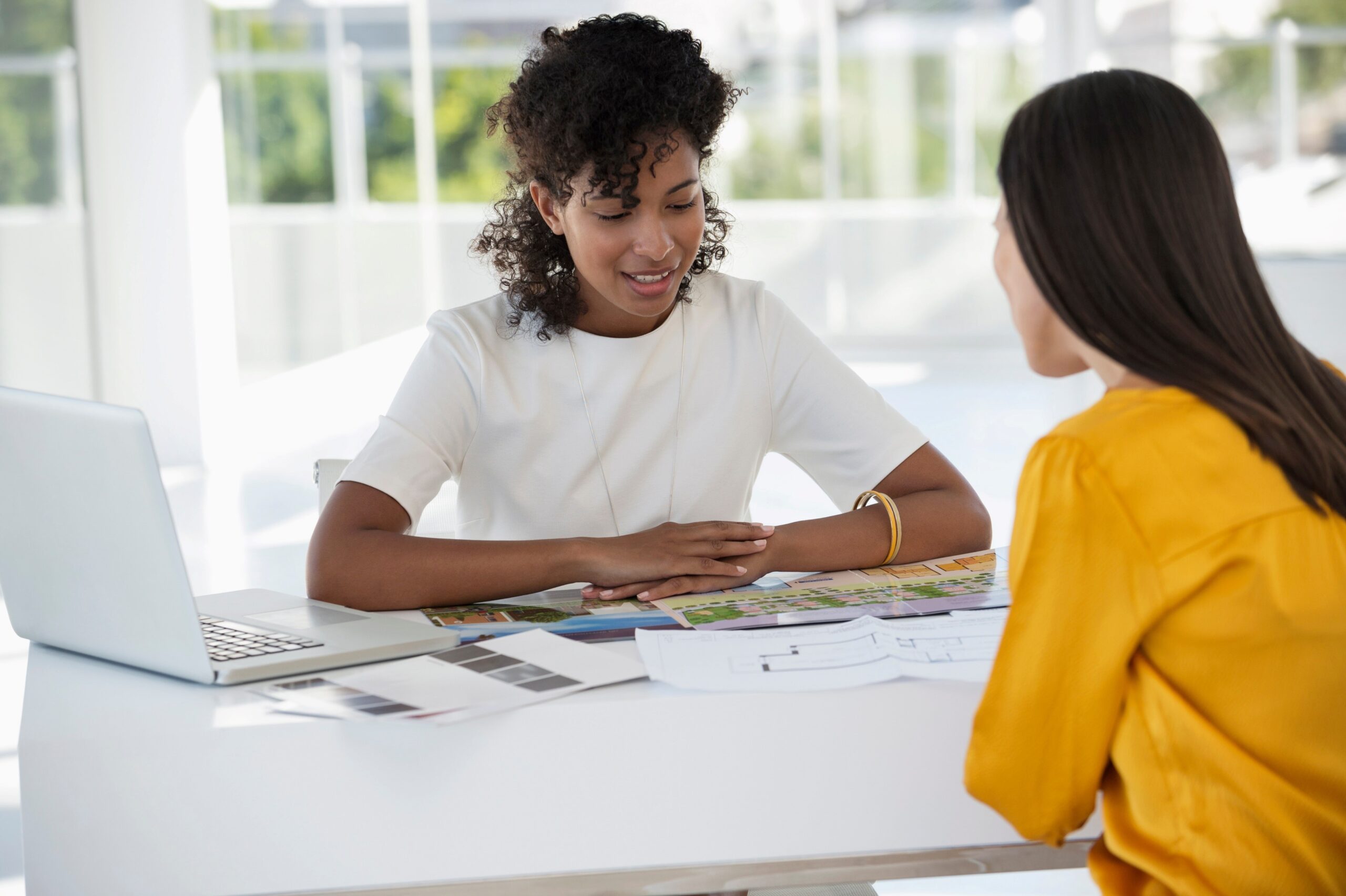 2 Frauen sitzen am Tischen und sprechen; Mitarbeitergespräch, Feedback